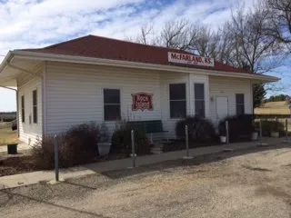 A white building with red roof and bushes in front of it.