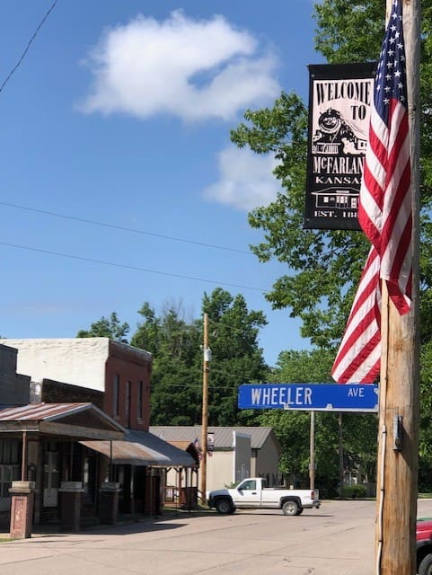 A pole with a street sign and an american flag on it.